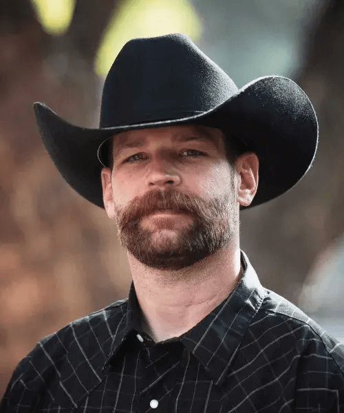 a man with brown beard wearing a shirt and a hat