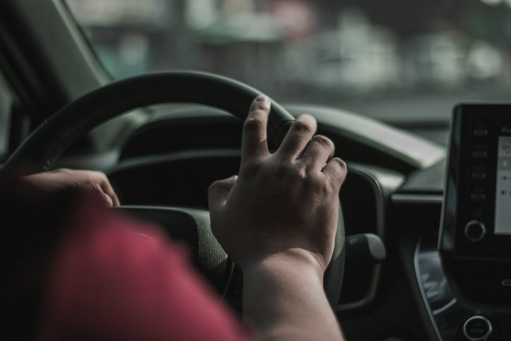 Interior view of a person driving a modern vehicle with a blurred view of the road through the windshield