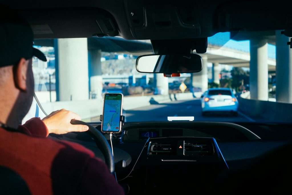 an interior view of a man driving a car under a overpass at day time